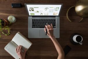 Student planning a college application at a laptop with a notebook